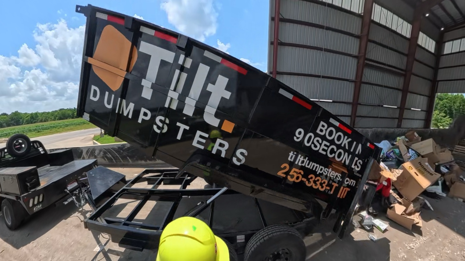 The Tilt Dumpsters trailer with its dump bed tilted up, unloading a real customer load